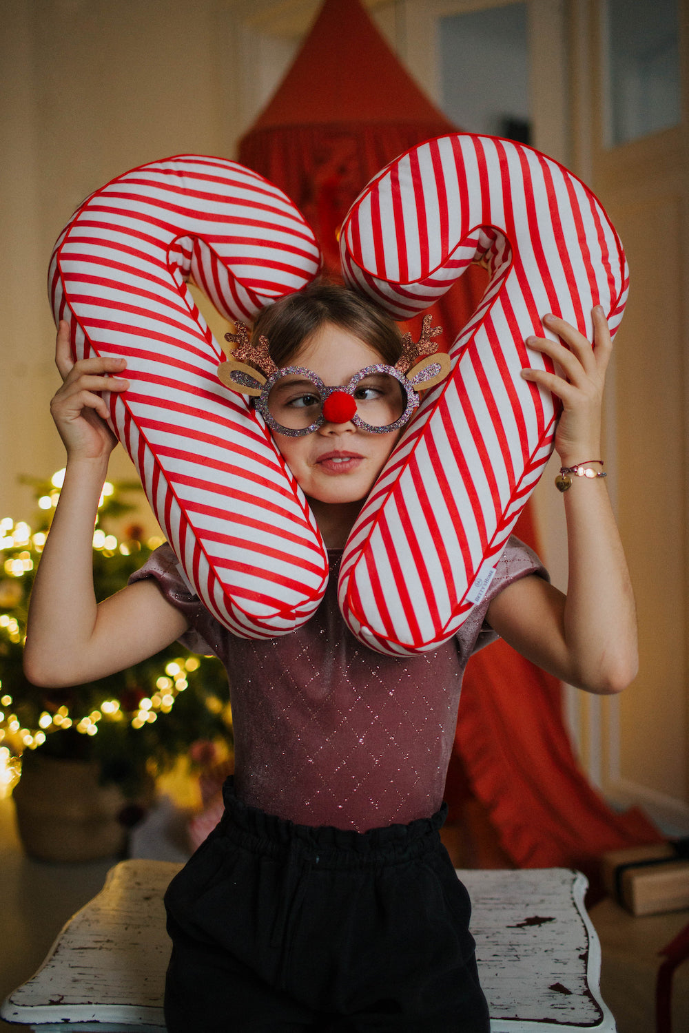 dziewczynka trzymająca dwie poduszki świąteczne w kształcie lasek cukrowych w paski od Bettys Home