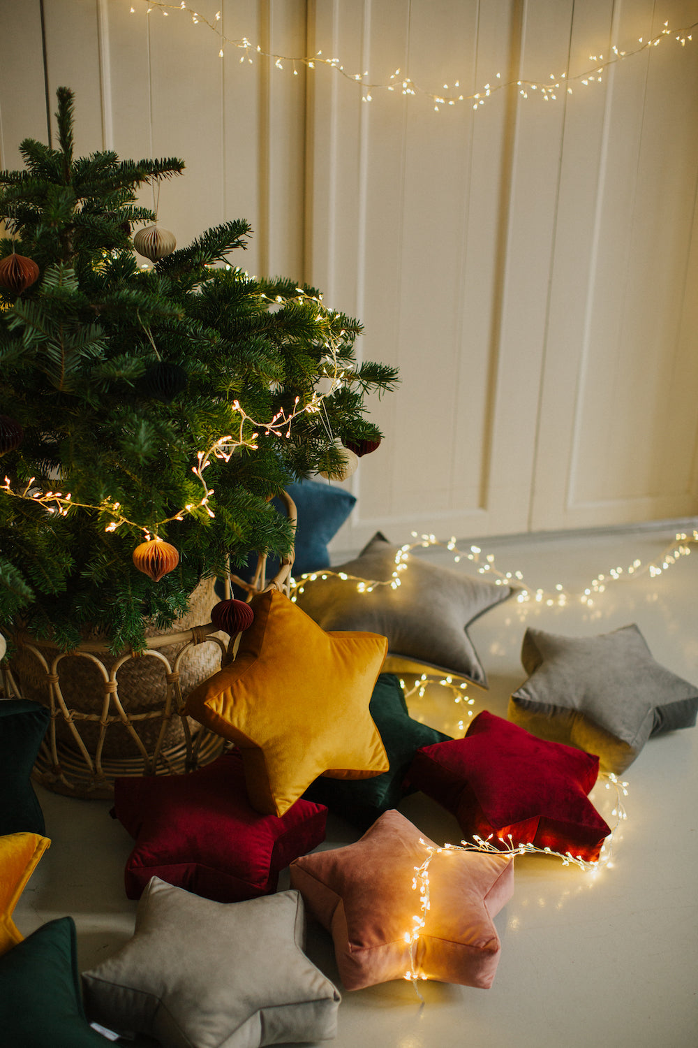 małe poduszki gwiazdki welurowe od Bettys Home leżące pod choinką jako dekoracją świąteczna na ścianę