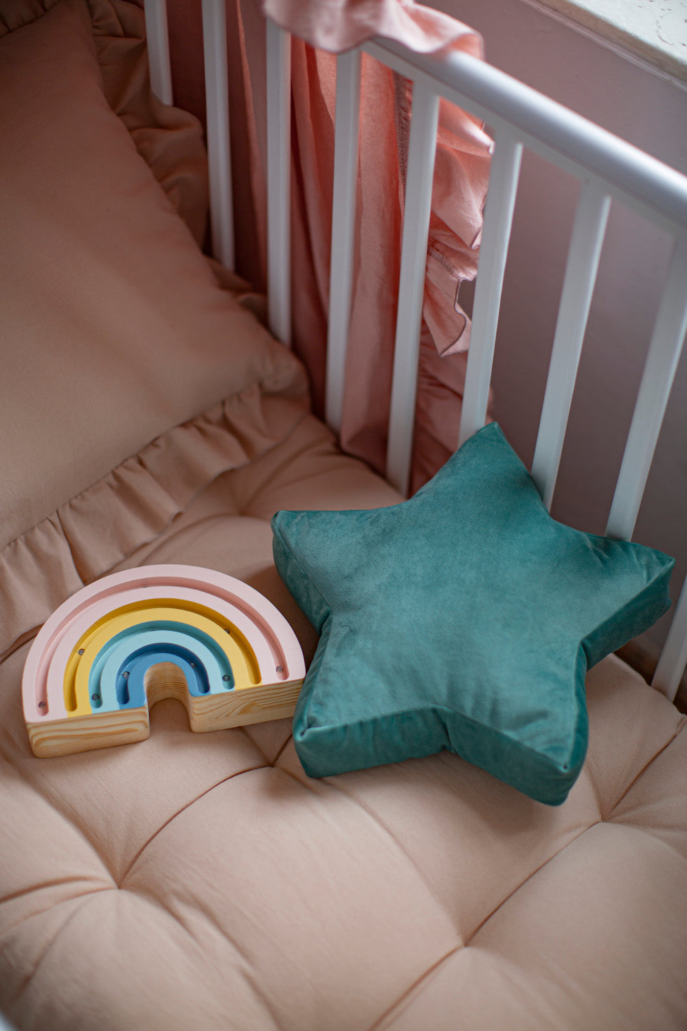 Mała poduszka gwiazdka miętowa welurowa od Bettys Home która leży w dziecięcym łóżeczku od lampki w kształcie tęczy 