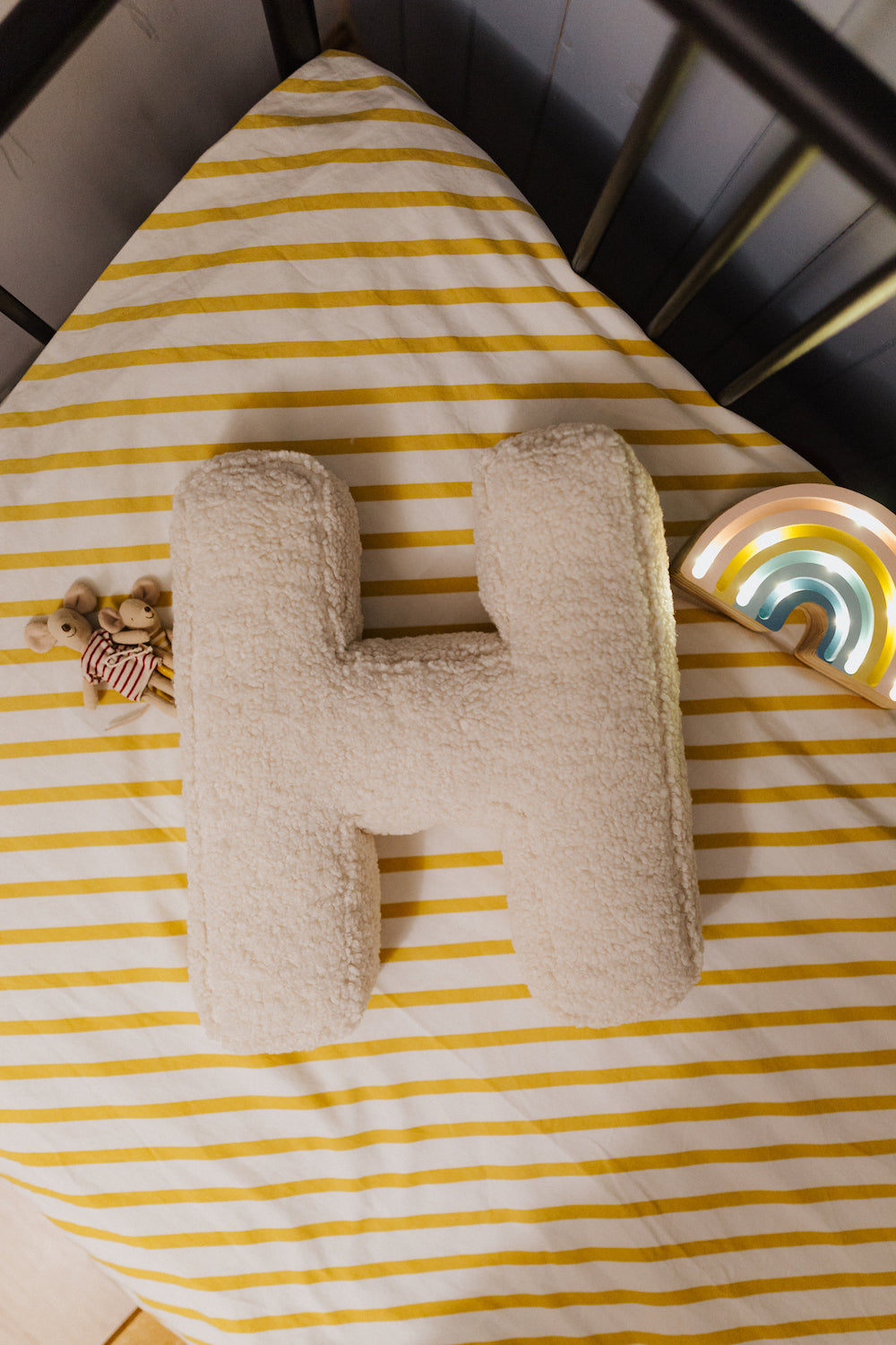 poduszka literka baranek H od Bettys Home leżąca na łóżeczku dziecka obok myszki Maileg Mouse
