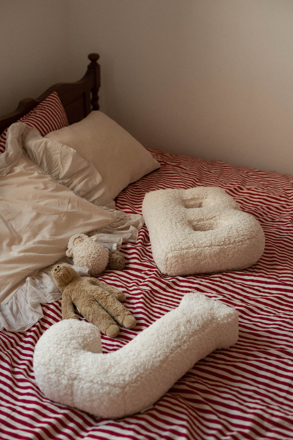 poduszka literka baranek B oraz J od Bettys Home leżąca na łóżku w sypialni