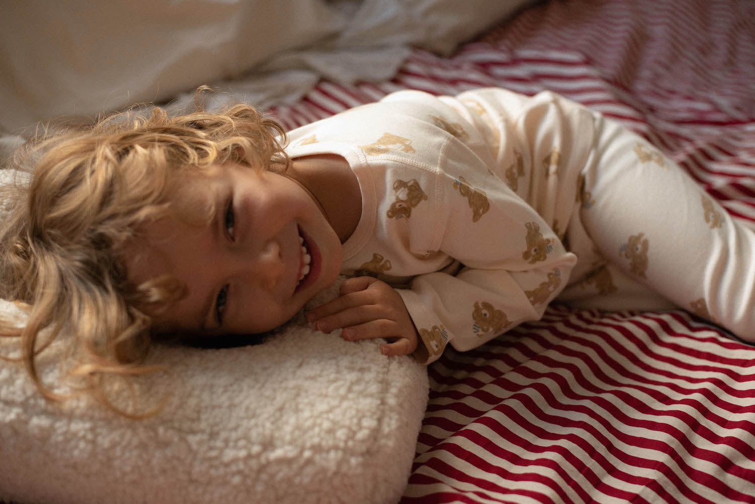 Mały chłopiec leżący na poduszce literce z baranka od Bettys Home przytulanka dekoracyjna dla dziecka 