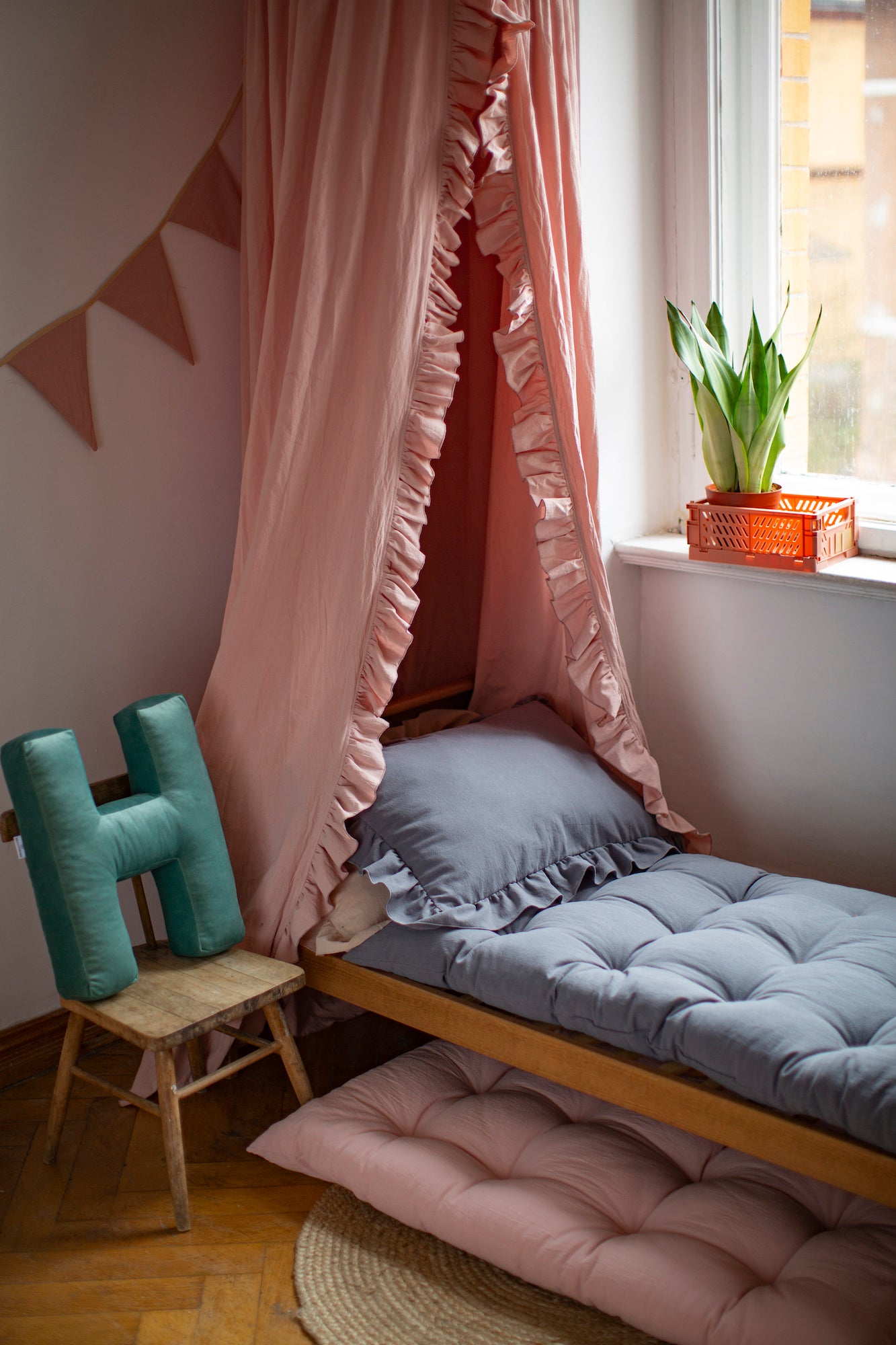 Pokój dziecięcy z baldachimem na łóżkiem a obok łóżeczka stoi poduszka literka welurowa H od Bettys Home