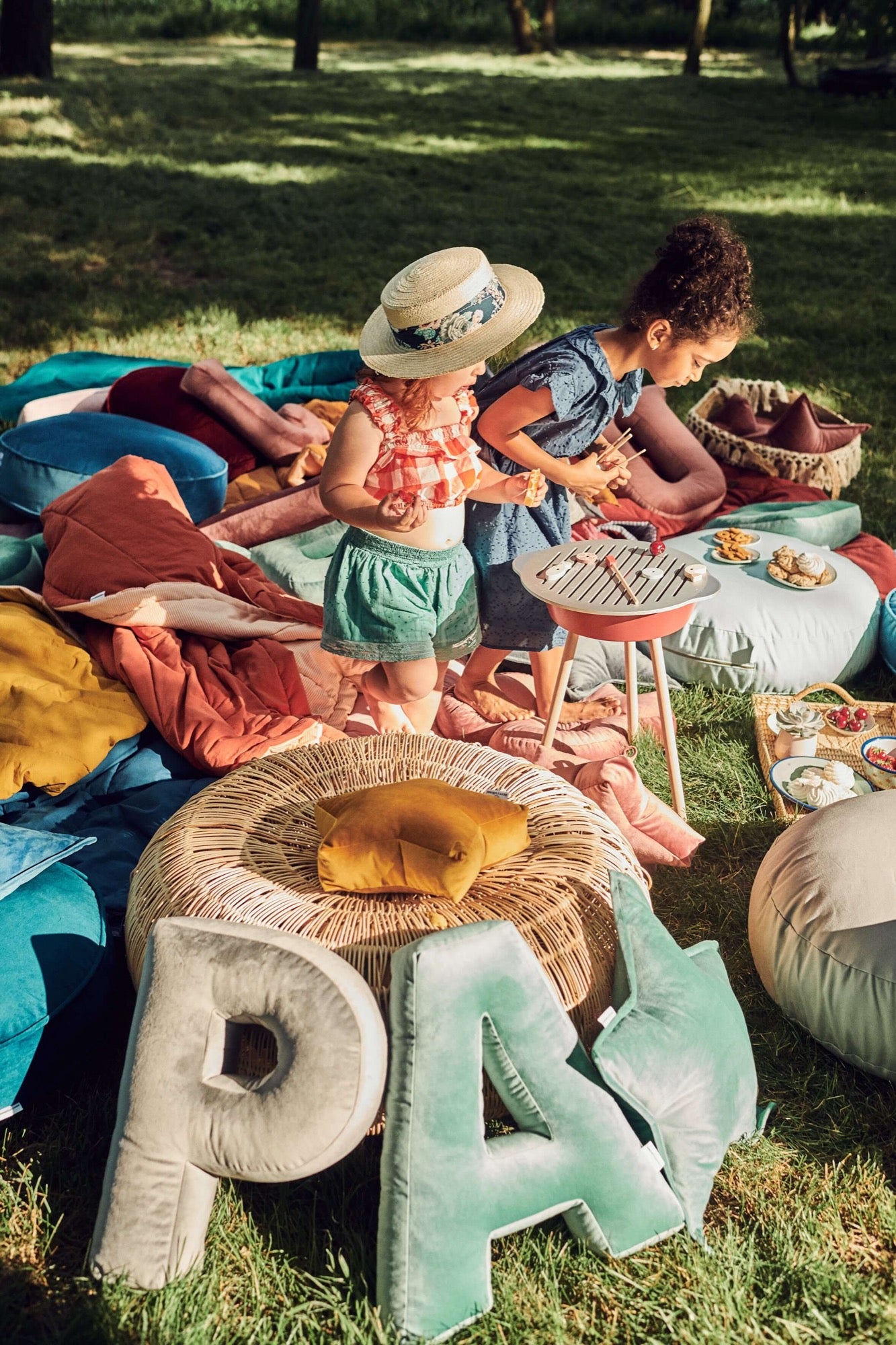 Poduszki literki welurowe od Bettys Home na trawie w ogrodzie w trakcie zabawy dzieci 