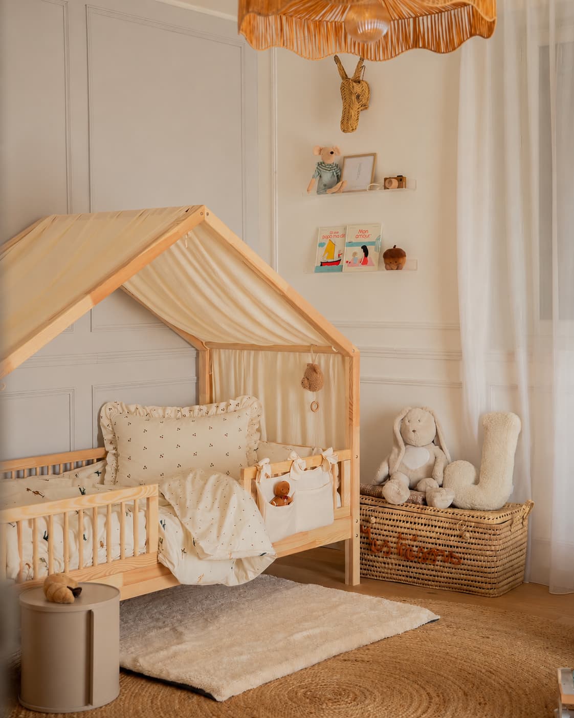 poduszka w wiśnie z falbanką od Bettys Home stylizowana na drewnianym łóżeczku w kształcie domku w neutralnym pokoju dziecięcym