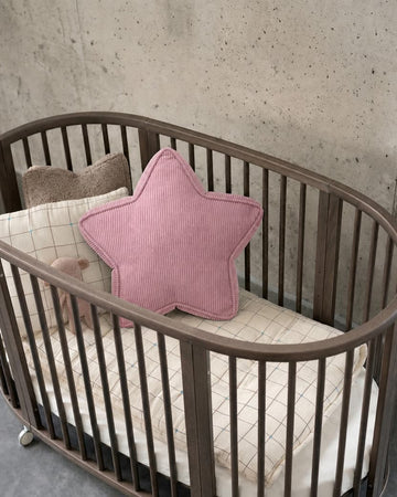 Różowa sztruksowa poduszka gwiazda w owalnym drewnianym łóżeczku na tle betonowej ściany - Bettys Home