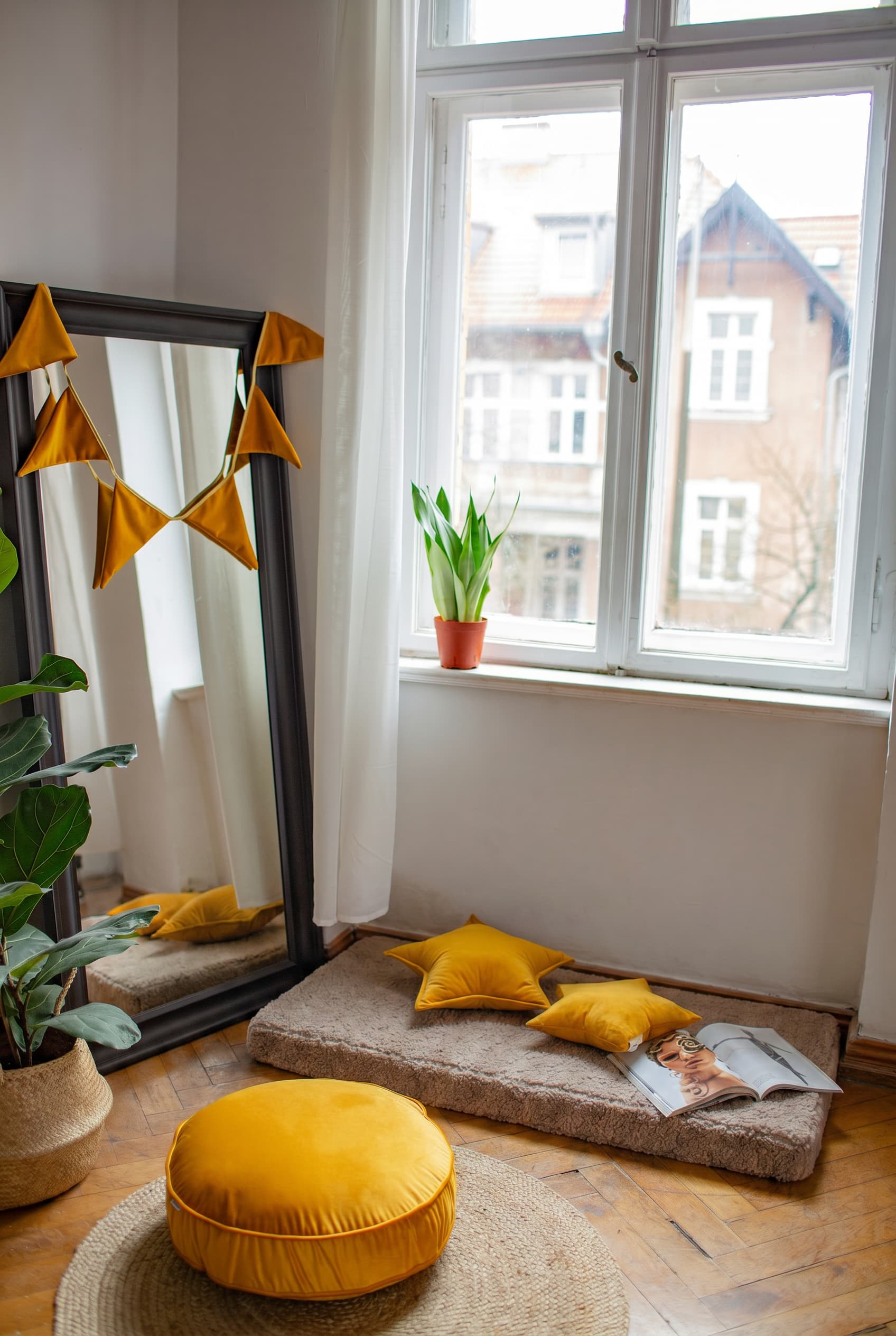 Przytulny kącik do czytania z materacem podłogowym bouclé mocha, musztardowymi poduszkami w kształcie gwiazdy i okrągłą pufą – by Bettys Home