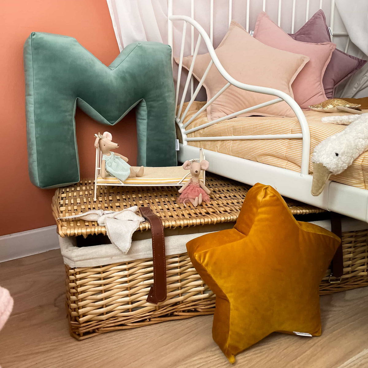 poduszka literka welurowa M od Bettys home stojąca przy dziecięcym łóżku na koszyku z wikliny