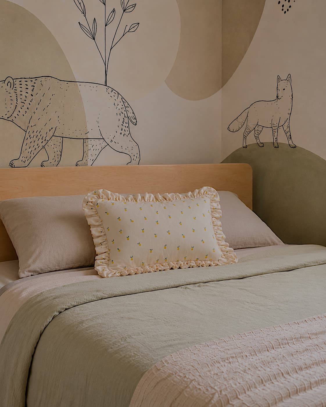 poduszka w cytryny z falbanką od Bettys Home stylizowana na drewnianym łóżeczku w kształcie domku w neutralnym pokoju dziecięcym