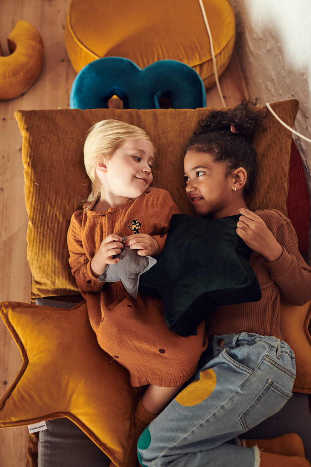 dwie dziewczynki w przedszkolu leżące na materacu trzymają poduszki gwiazdki od bettys home