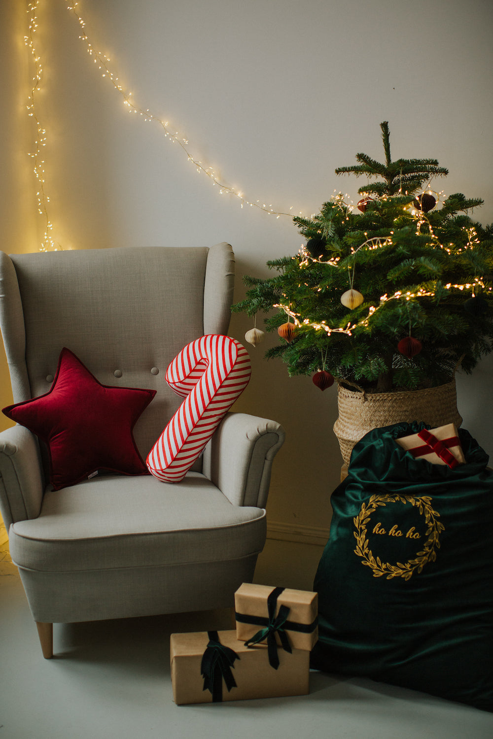 Poduszka gwiazda czerwona na fotelu obok świątecznej poduszki lizaka od Bettys Home obok choinki  