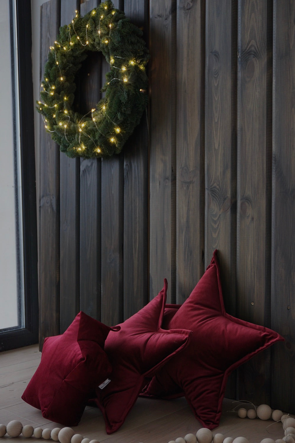 poduszki gwiazdki czerwone welurowe od Bettys Home na tle drewnianej ściany 