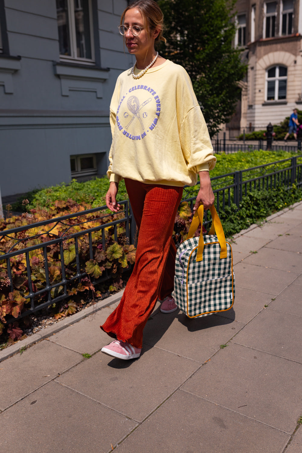 kobieta idąca chodnikiem z zielonym plecakiem w kratkę od Bettys Home, lekki plecak damski miejski, dobry plecak miejski 