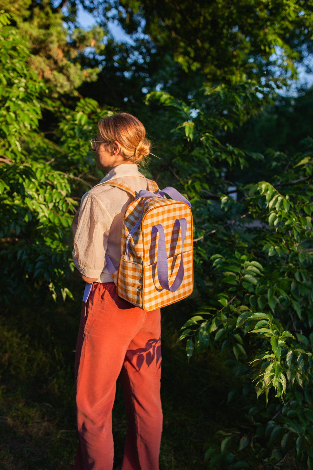 kobieta na spacerze w lesie z plecakiem w kratkę żółtym od Bettys Home na plecach plecak do samolotu bagaż podręczny