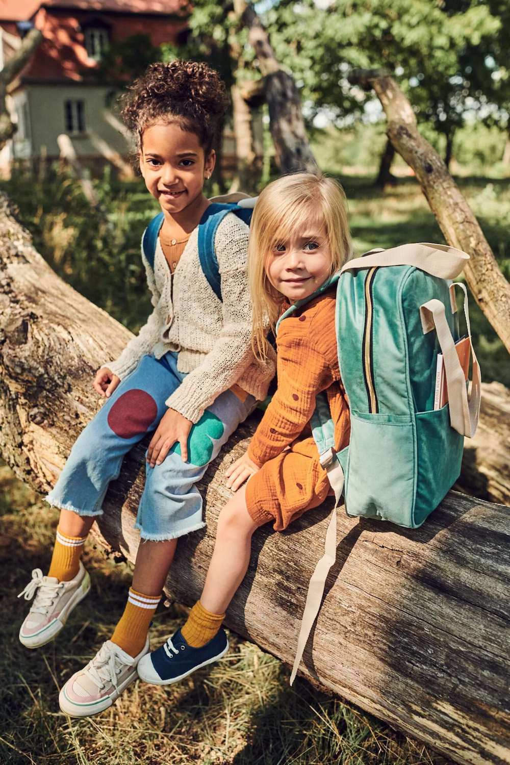 dziewczynki siedzące na drzewie w parku mają duże plecaki welurowe od Bettys Home, plecak do szkoły dla dziewczynki 