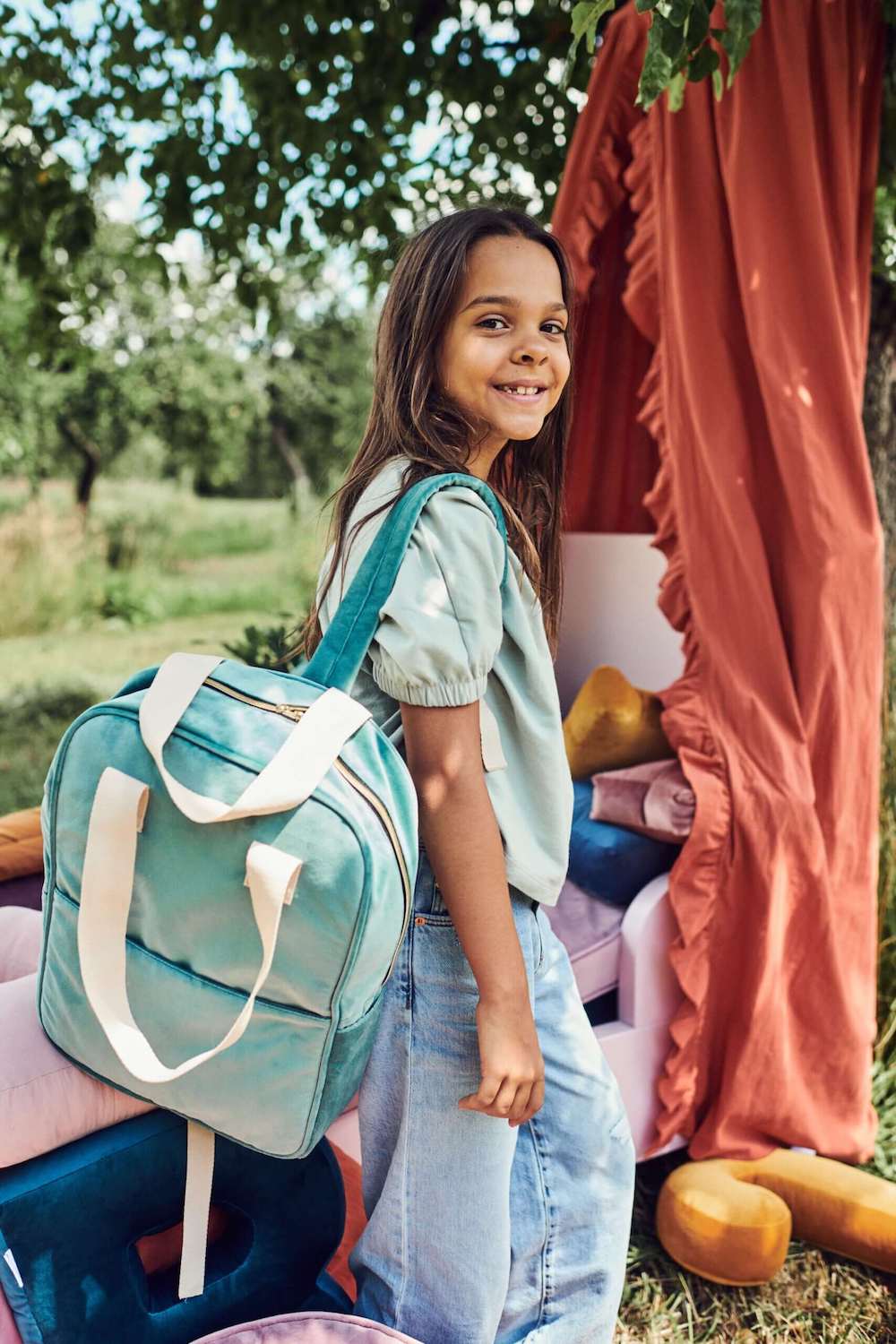 dziewczynka w ogrodzie ma na ramieniu duży plecak welurowy w kolorze miętowym od Bettys Home, plecak do szkoły damski 