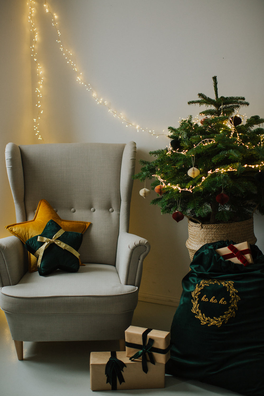 mała poduszka gwiazdka owinięta wstążką na fotelu obok choinki i worka na prezenty welurowego od Bettys Home