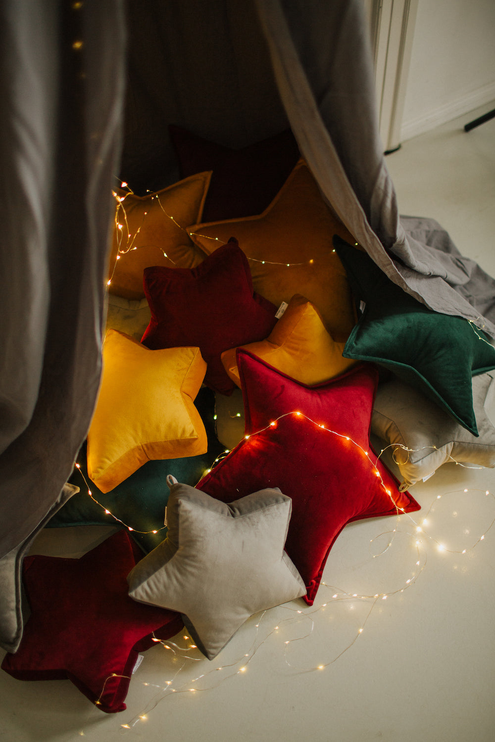 zestaw poduszek gwiazdek od Bettys Home pod baldachimem z lampkami świątecznymi 