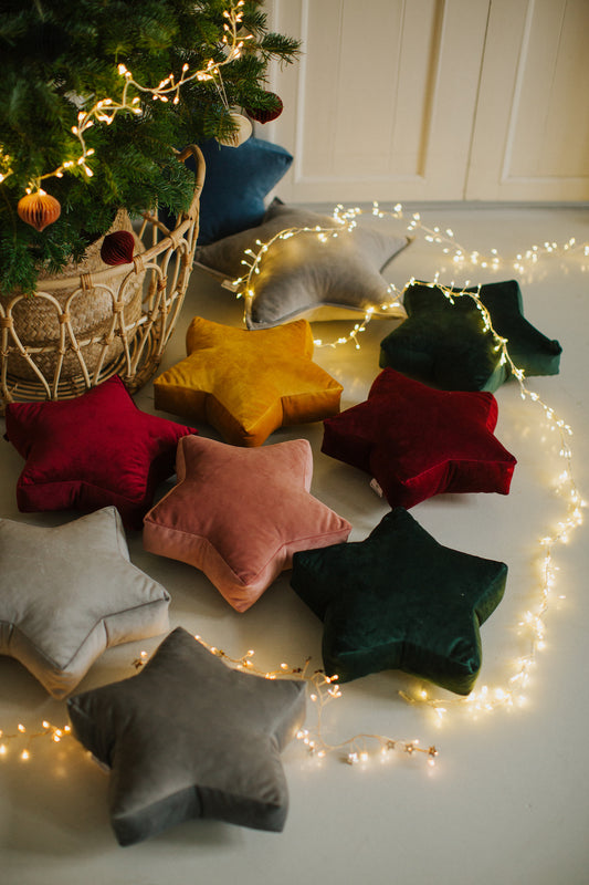 Małe poduszki gwiazdki welurowe od Bettys Home obok choinki. Świąteczne zawieszki na ścianę 