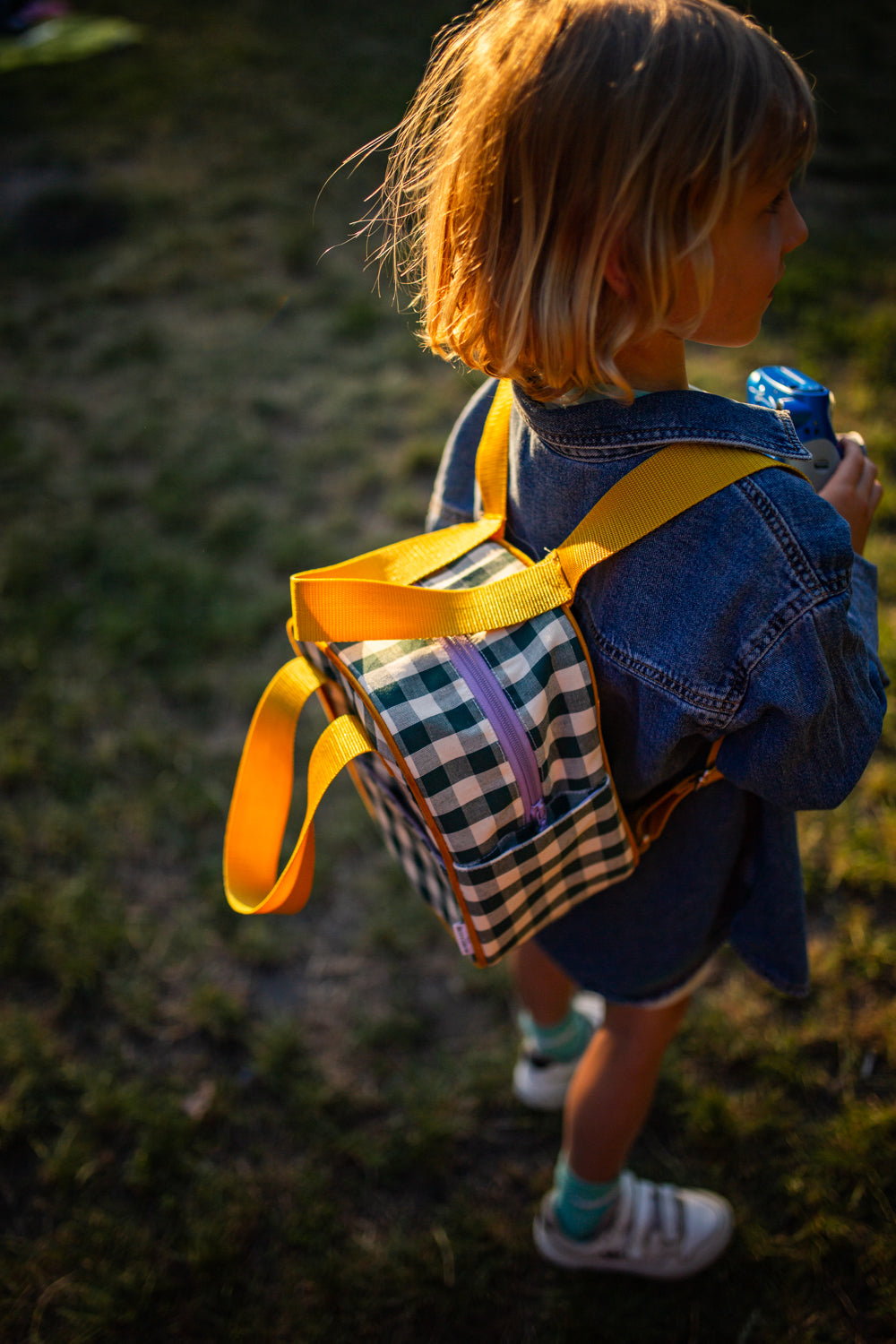 mały chłopiec w parku z małym zielonym plecakiem w kratkę od Bettys Home, plecak dla przedszkolaka