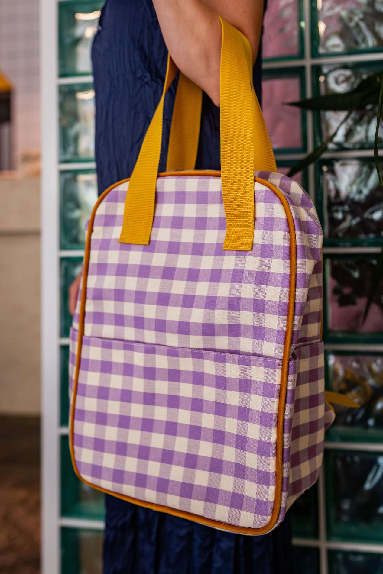 kobieta w kawiarni z przewieszonym przez rękę plecakiem fioletowym w kratkę od bettys home. modne plecaki miejskie 