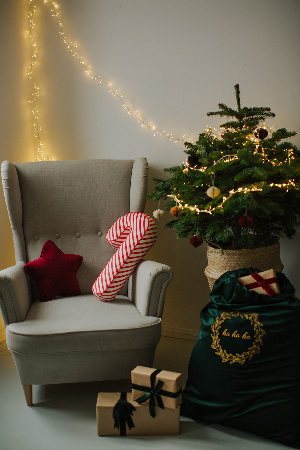 świąteczne poduszki laski w biało czerwone paski od Bettys Home leżąca na fotelu jako ozdoba świąteczna obok choinki 