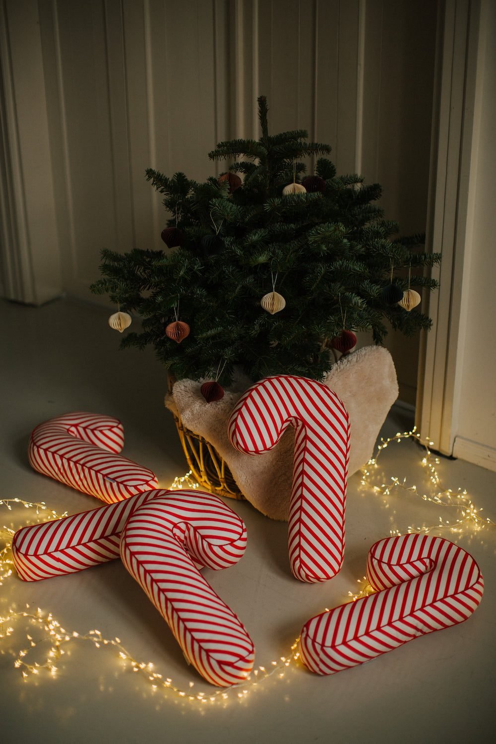 świąteczne poduszki laski w biało czerwone paski od Bettys Home leżące pod choinką jako dekoracje świąteczne