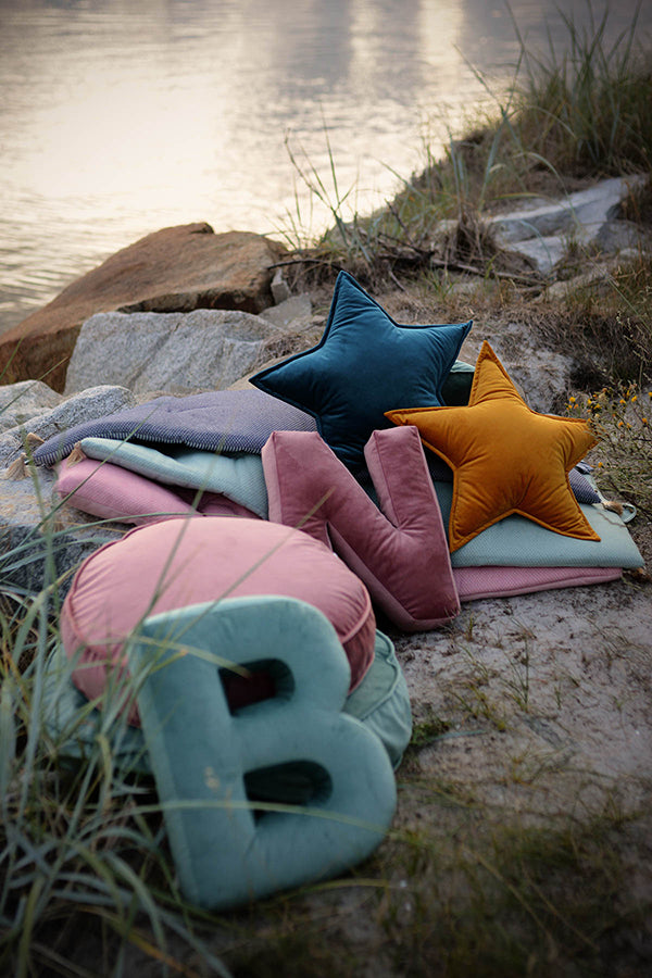 Poduszki literki welurowe od Bettys Home na piasku przy morzu oraz poduszki w kształcie gwiazdy