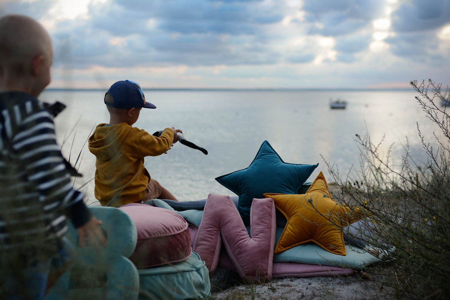 Chłopcy nad morzem obok poduszek liteereek welurowych i poduszek gwiazdek welurowych od Bettys Home