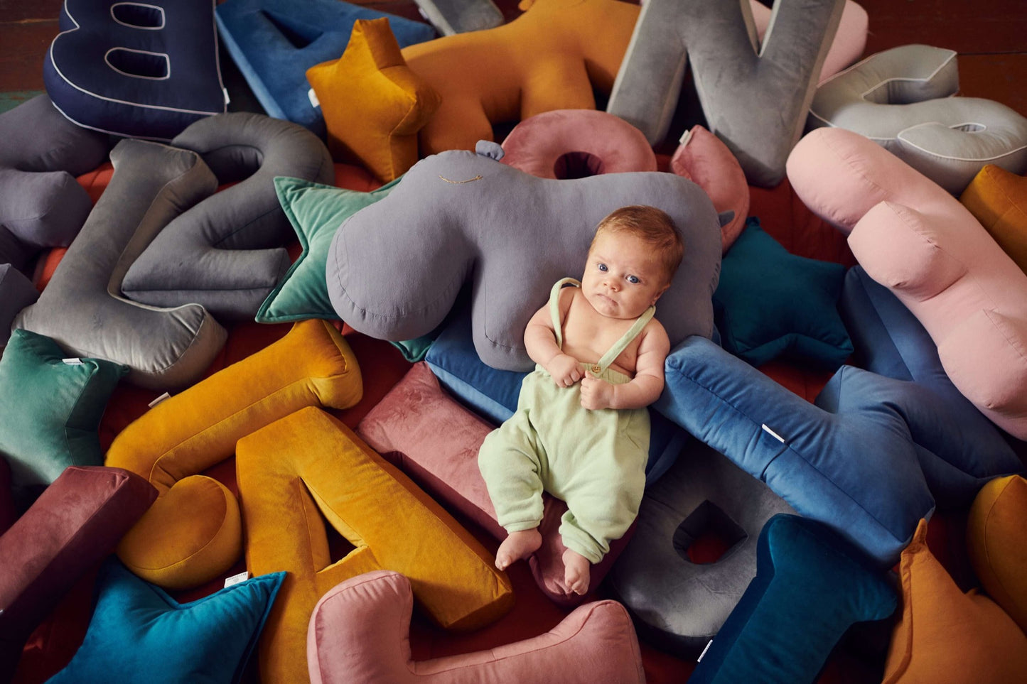 Mały chłopiec leżący na poduszkach literkach welurowych od Bettys Home w wielu kolorach 