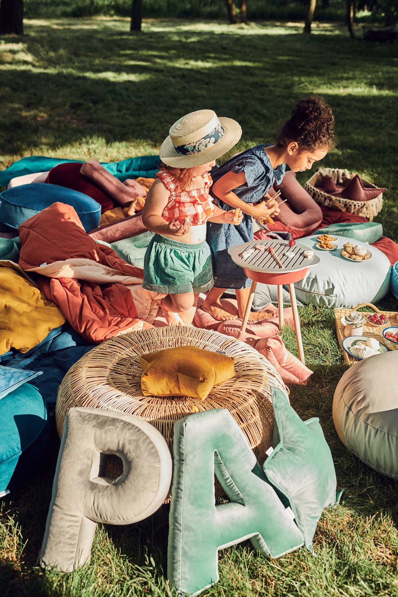 piknik dziewczynek w ogrodzie obok poduszek literek welurowych od Bettys Home 