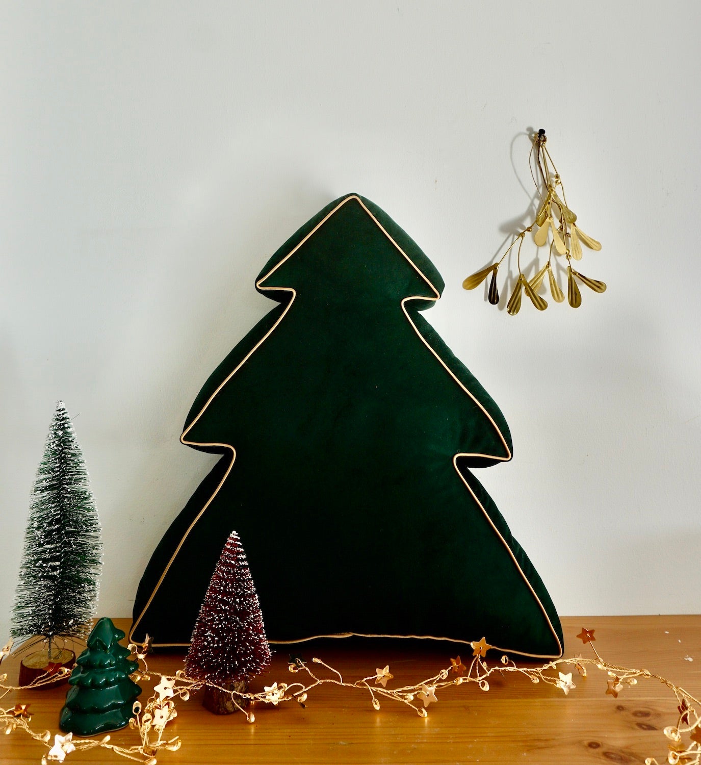 Zielona poduszka świąteczna choinka od Bettys Home stoi na regale 