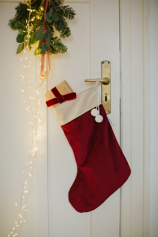 dekoracyjna skarpeta świąteczna w kolorze czerwonym wino od Bettys Home  zawieszona na drzwiach 