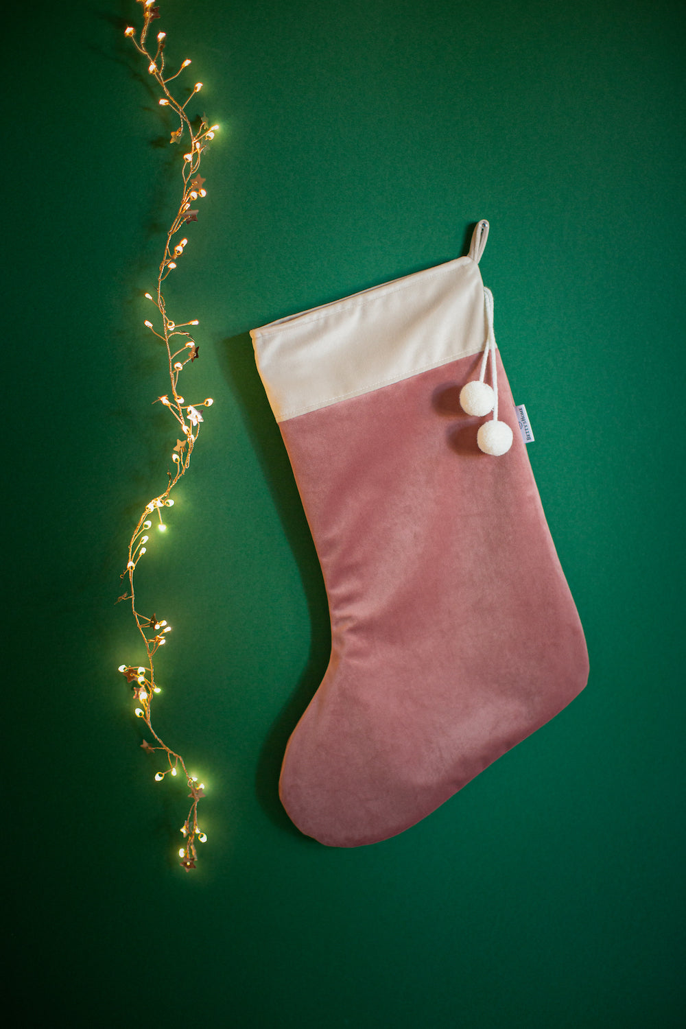 różowa świąteczna skarpeta na prezenty od Bettys Home na tle zielonej ściany dekoracje salonu