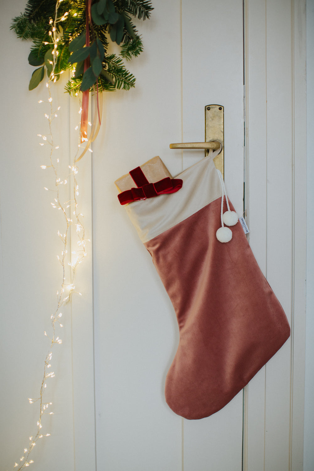 Świąteczna skarpeta na prezenty od Bettys Home wisząca na klamce od drzwi jako dekoracja świąteczna do salonu