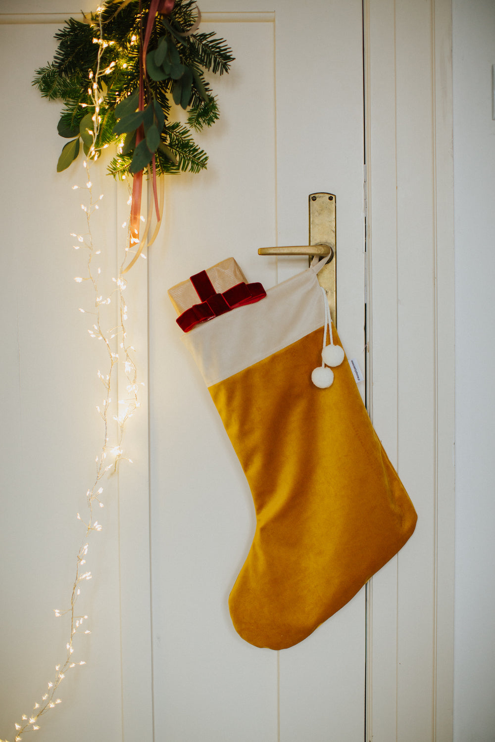 świąteczna skarpeta żółta od Bettys Home wisząca na drzwiach jako dekoracja świąteczna do każdego wnętrza 