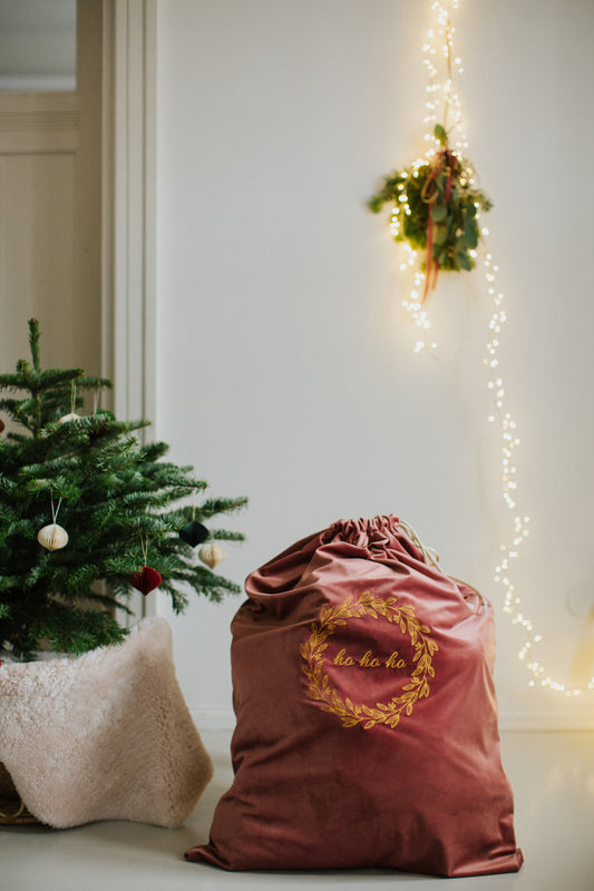 świąteczny worek na prezenty różowy od Bettys Home stoi obok choinki.