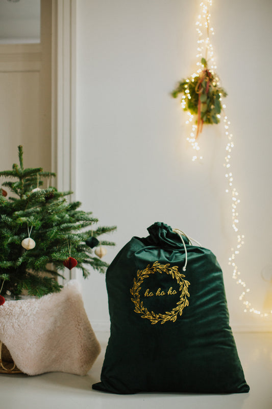 świąteczny worek na prezenty od Bettys Home stojący obok małe choinki 