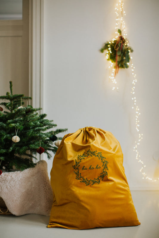 świąteczny worek na prezenty w kolorze żółtym od Bettys Home obok choinki