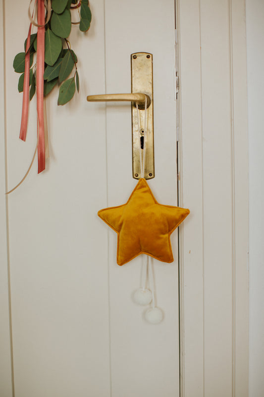 świąteczna zawieszka gwiazdka w kolorze żółtym wisząca na klamce od drzwi. dekoracja świąteczna