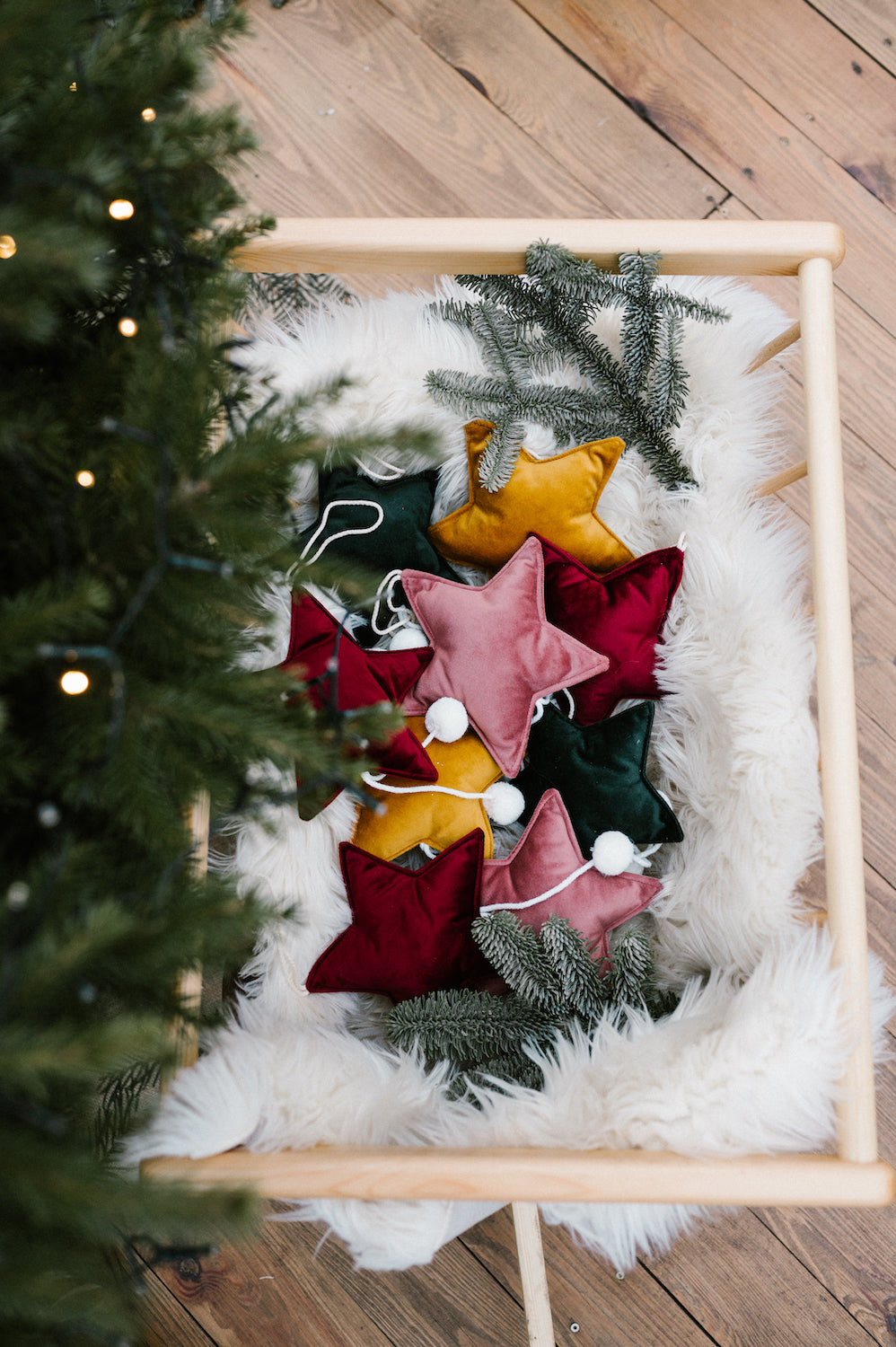 małe zawieszki gwiazdki od bettys home w drewnianym wózku świątecznym obok choinki